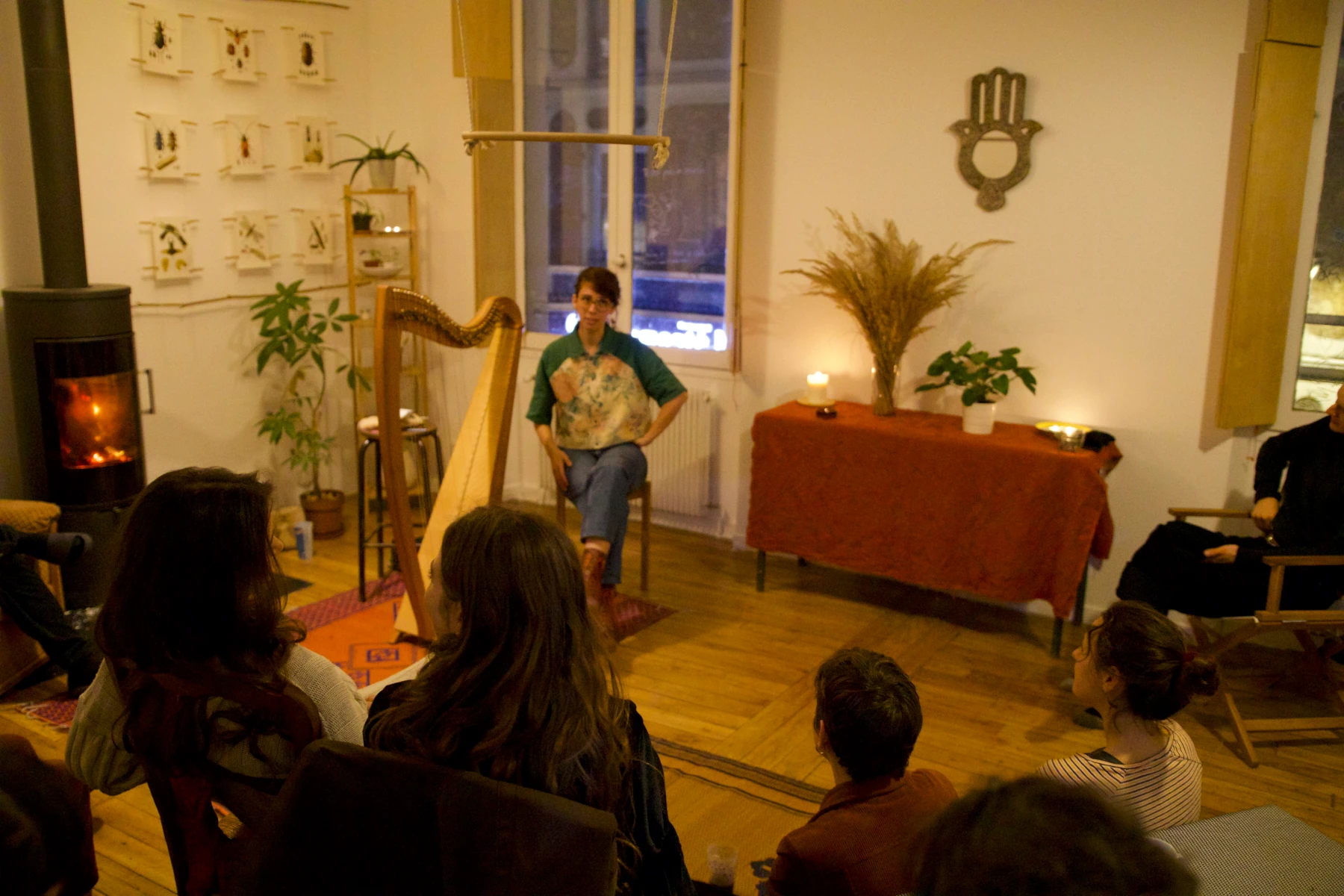 Un concert dans un appartement à Lyon avec les spectateurs assis par terre ou sur des chaises, écoutant une pianiste et un joueur de Oud.