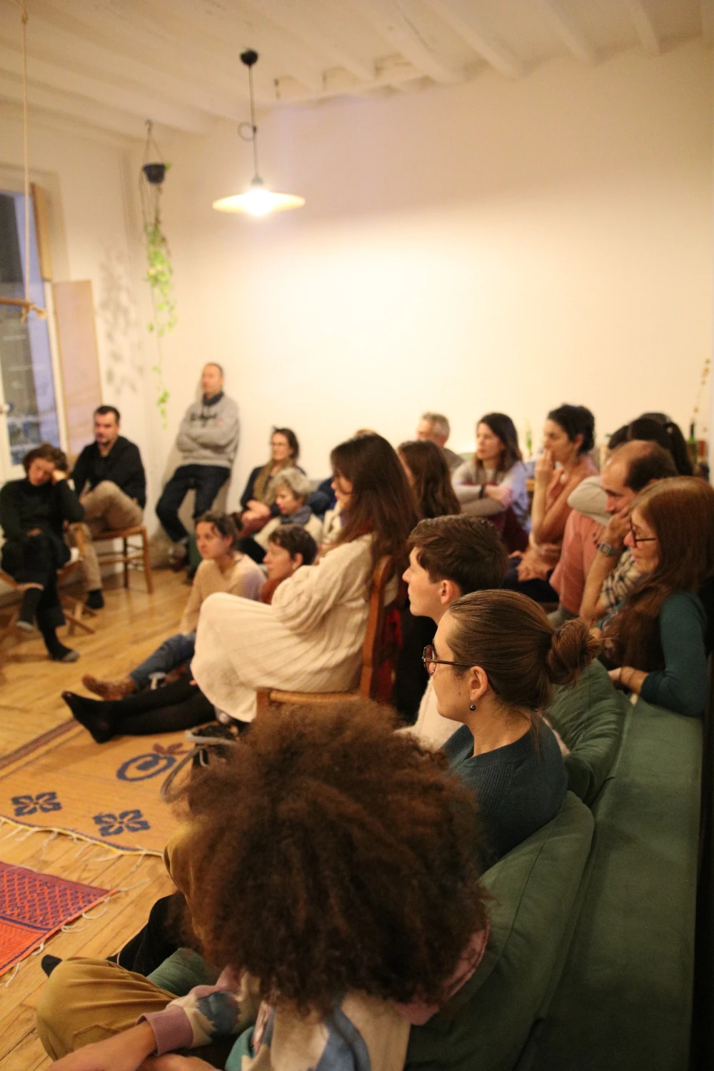 Un concert dans un appartement à Lyon avec les spectateurs assis par terre ou sur des chaises, écoutant une pianiste et un joueur de Oud.